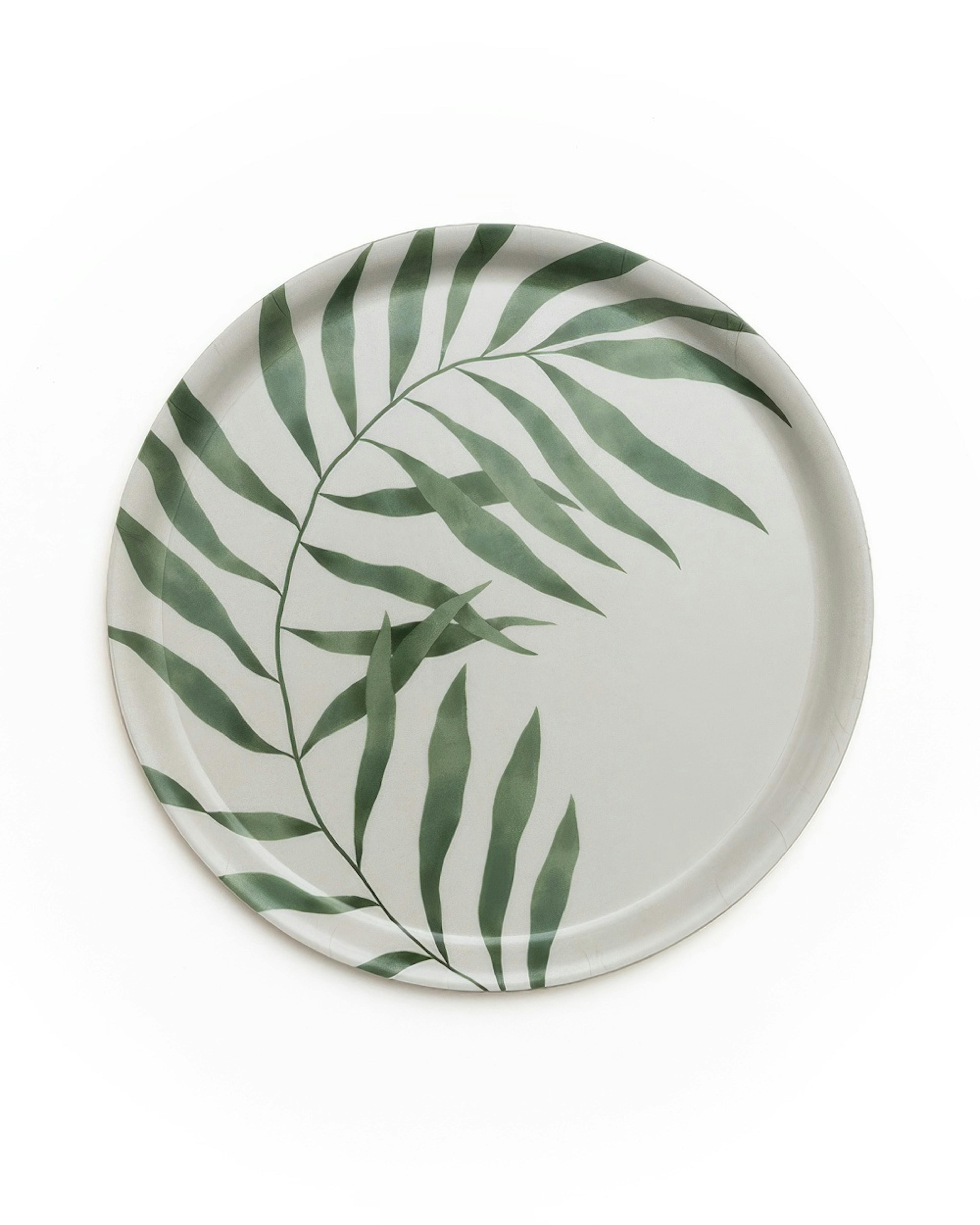Vassoio rotondo Palm Leaf con foglia di palma verde scuro che si estende su una superficie bianca. Vassoio decorativo, accessori
