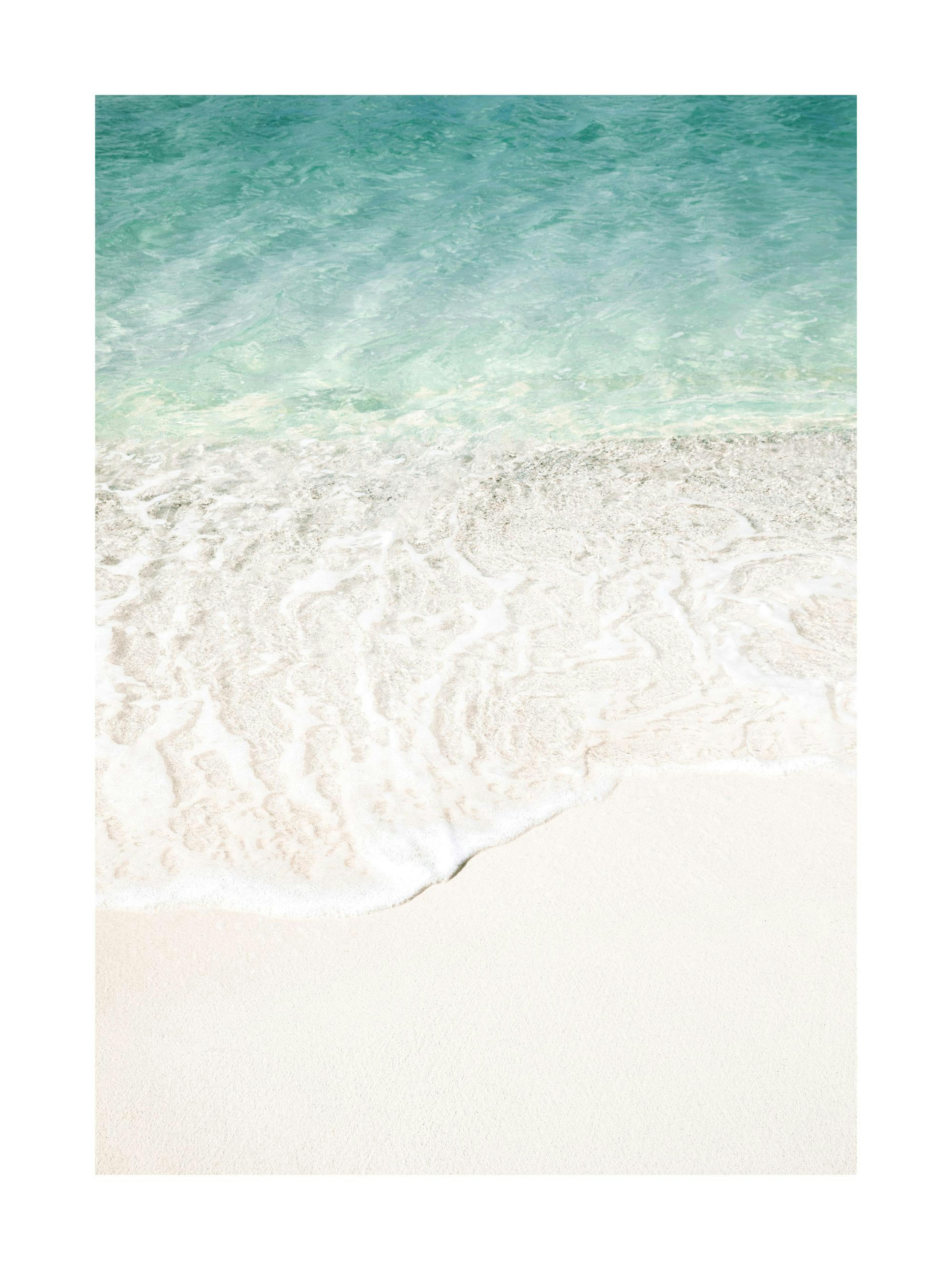 Poster van wit zandstrand met turquoise zeewater, hangend in een slaapkamer boven een betonnen nachtkastje.