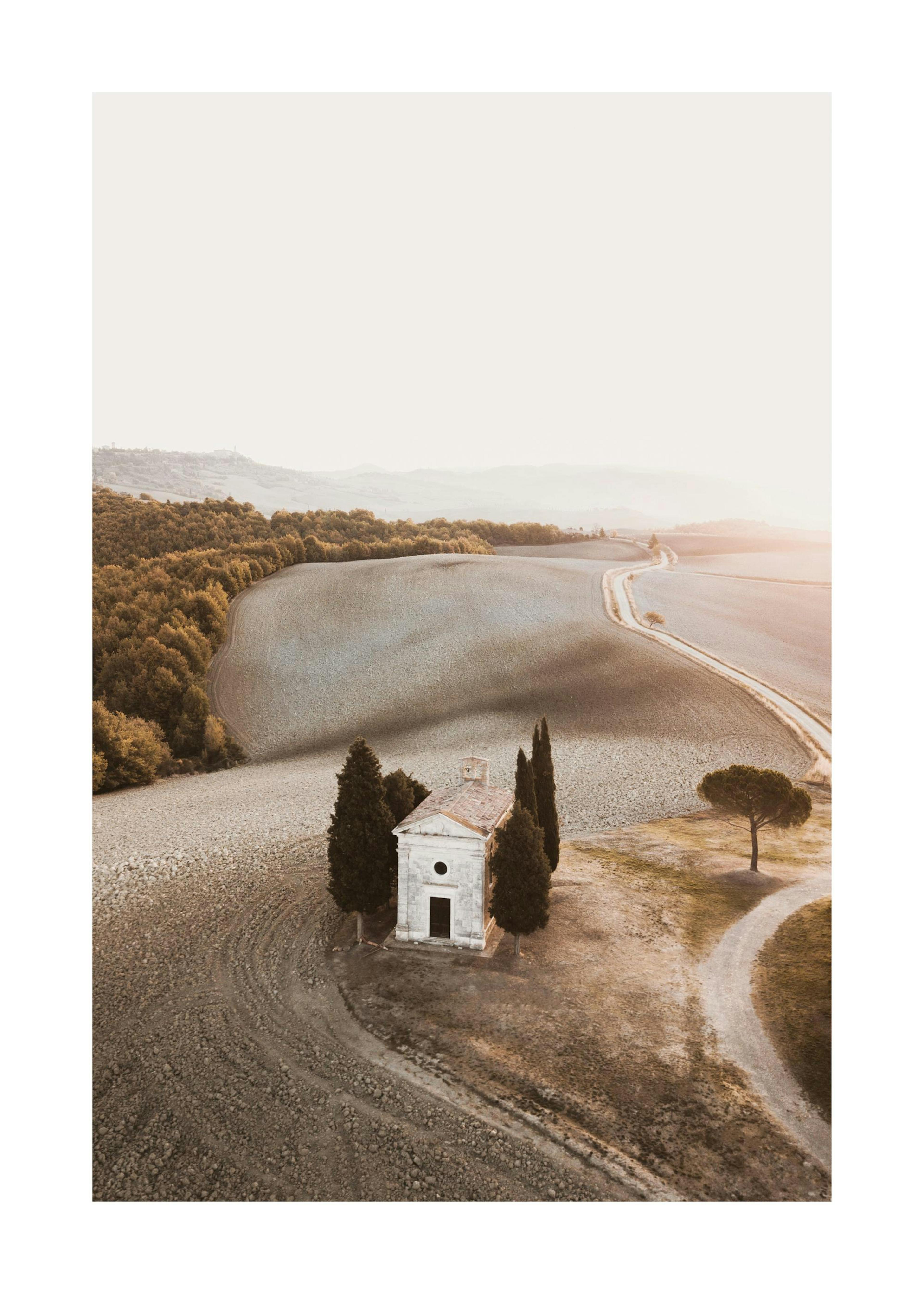 Kapel in Toscane, midden in een veld met bomen en een kronkelend pad, zonsonderganglicht.