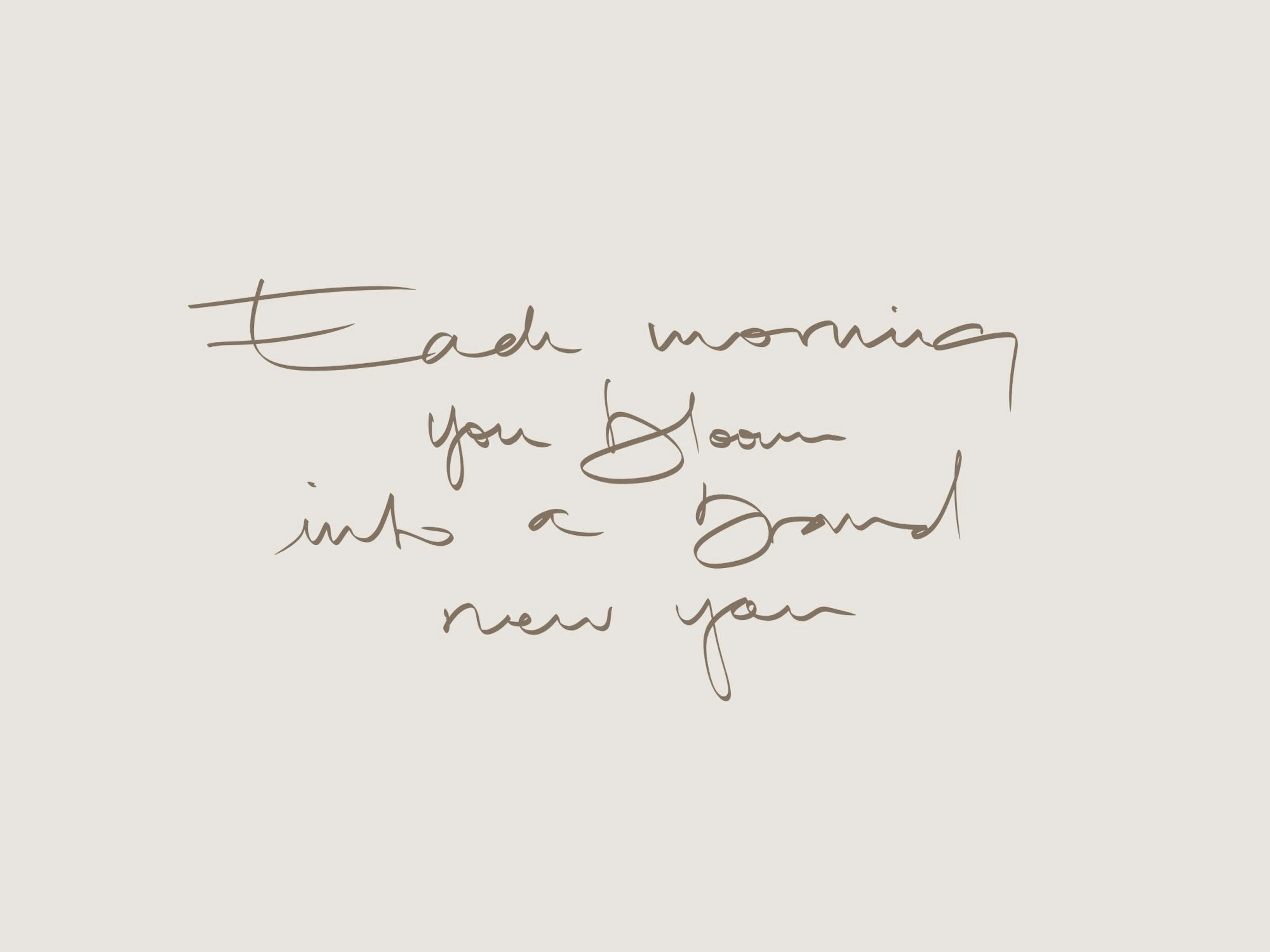 Poster med texten Each morning you bloom into a brand new you hänger ovanför en säng med mörkbrun sänggavel.